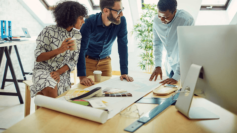 a group of people looking over an architectural blueprint