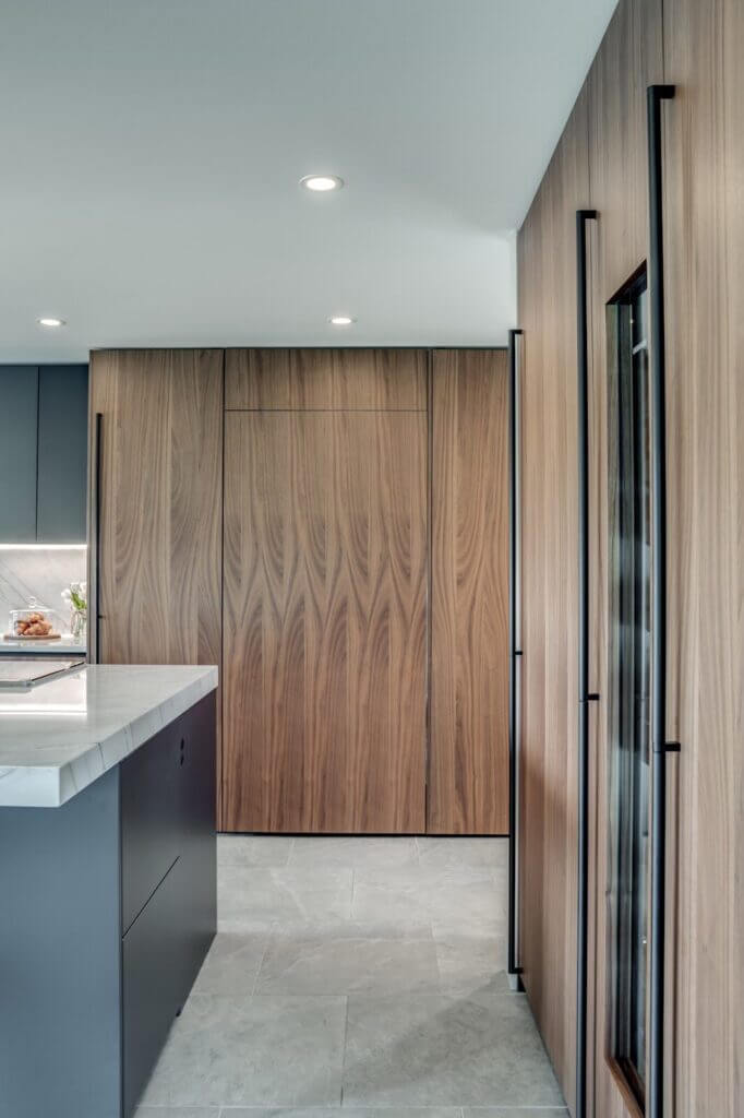 Luxury kitchen design showcasing rich wood-paneled cabinetry, modern integrated appliances, and a sleek marble-topped island with minimalist aesthetics.