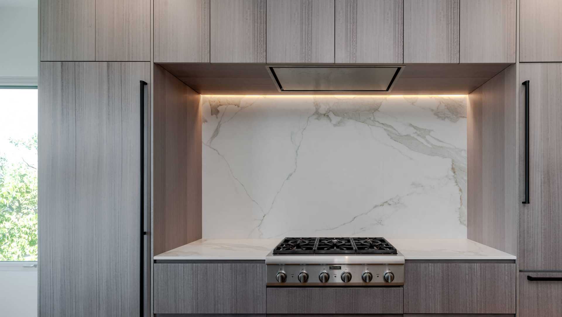 A modern kitchen featuring a high backsplash in elegant marble, seamlessly extending from the countertop to the cabinets—perfect for a luxury kitchen backsplash design.