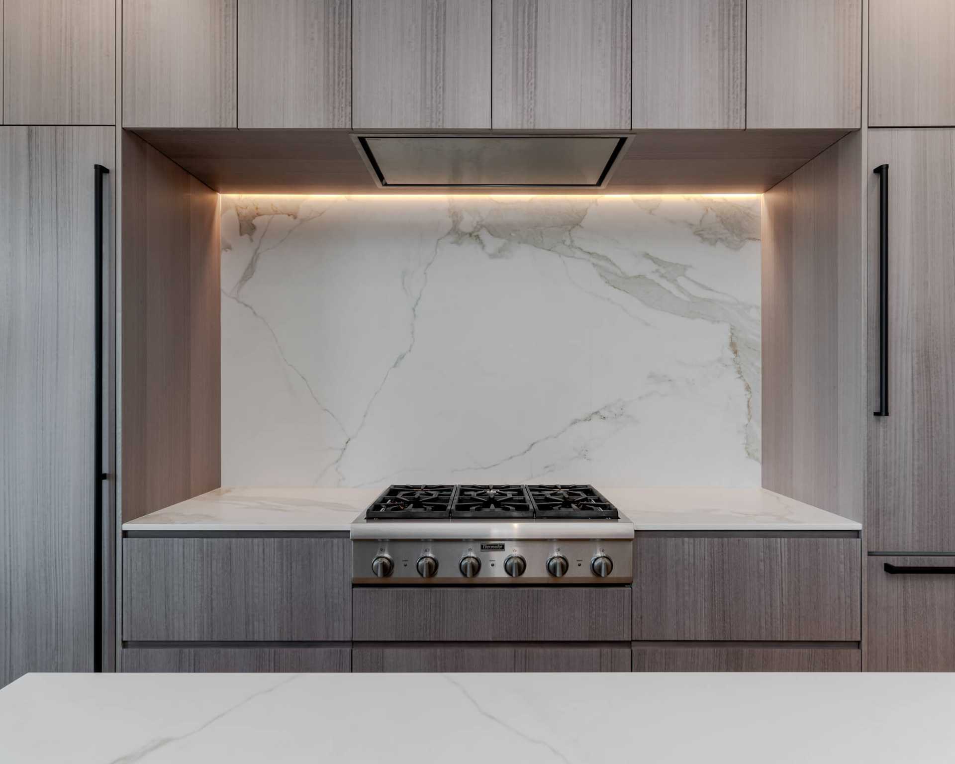 A modern kitchen featuring a high backsplash in elegant marble, seamlessly extending from the countertop to the cabinets—perfect for a luxury kitchen backsplash design.